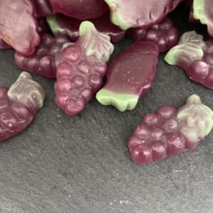 Mayceys Sour Grape gummies on a dark stone background