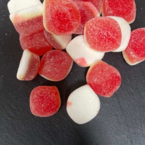 Peach and white coloured gummies on a grey stone background